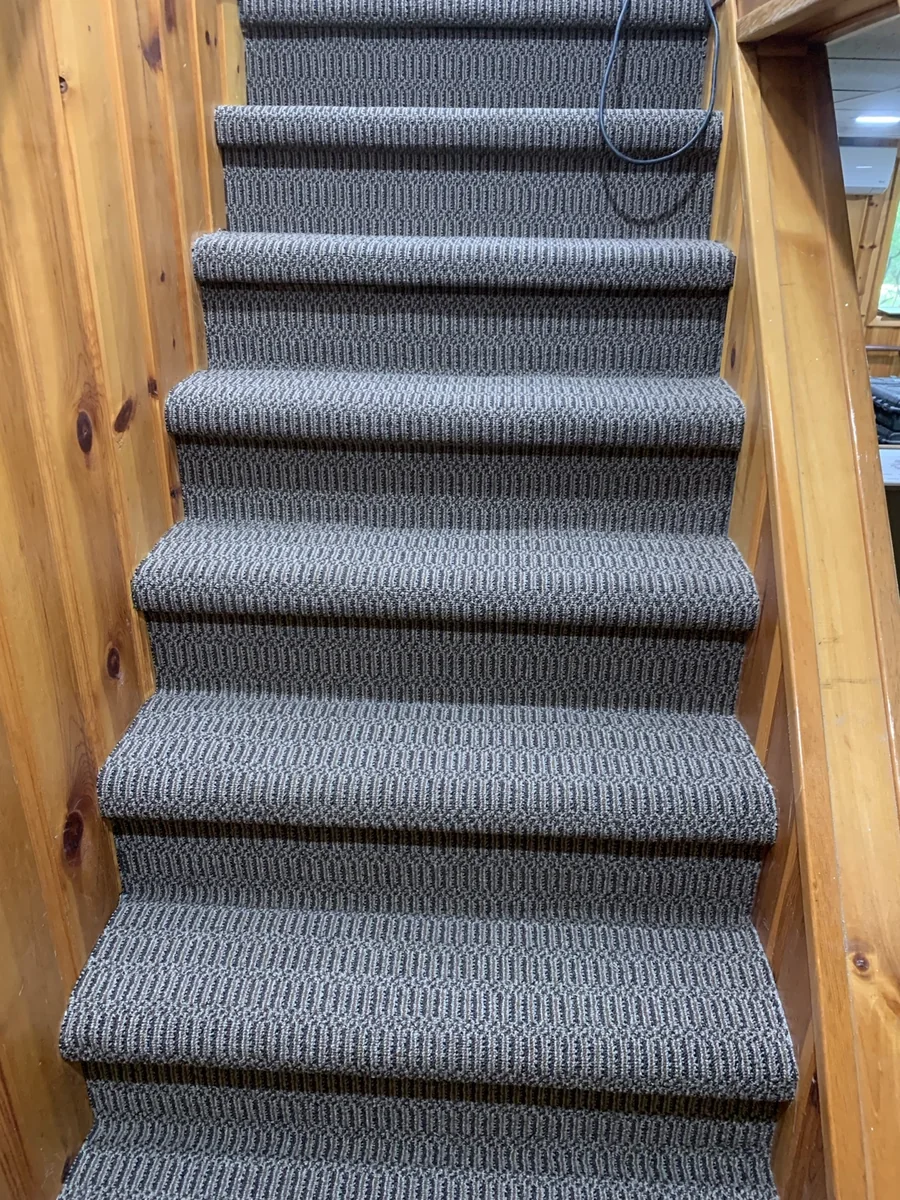 Patterned carpet steps installed between wood stair railings